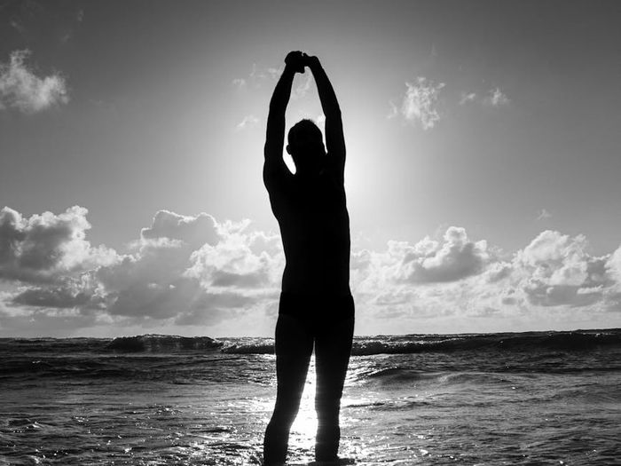 A silhouette of a man stretching against a sunrise.