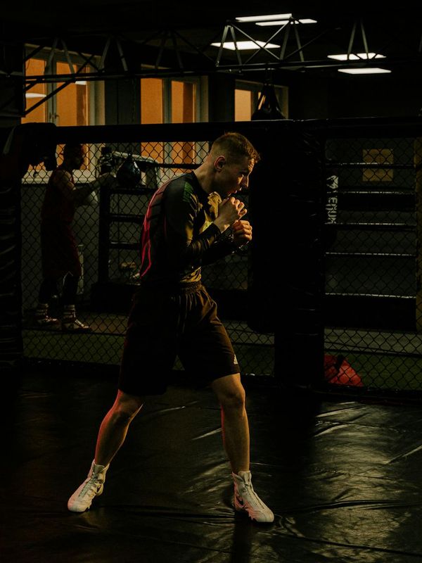 Focused man performing a strength exercise in a dark gym.